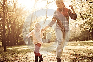 Mother and her little daughter holding hands and jumping