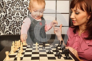 Mother and her little daughter playing chess