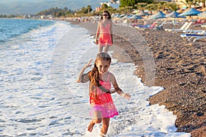 Mother and her little daughter playing and running on the beach
