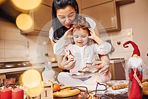 Mother with her little daughter preparing food on kitchen and have fun