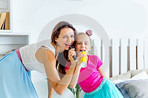 Mother and her little daughter sing into the microphone together