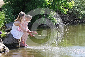 Mother and her little daughter squirting water at the lake photo