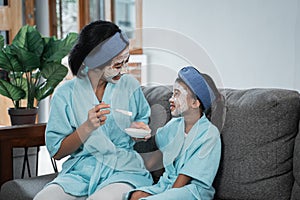 a mother and her little girl smiling wearing face masks look at each other while sitting