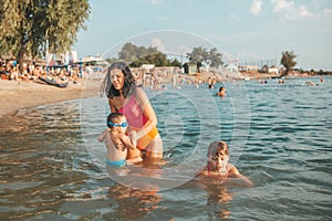 Mother, her little son and daughter making fun in the water