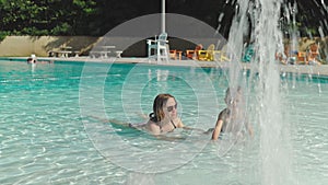 Mother and her little son having fun in a swimming pool