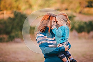 Mother and her little son in a knitwear have a walk in a forest