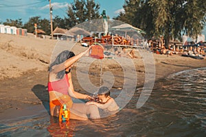 Mother and her little son playing with beach toys in the water