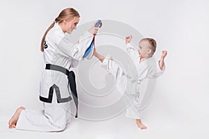 Mother her little son practicing martial arts over white background