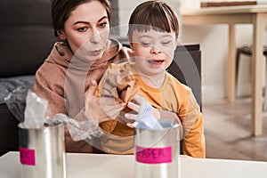 Mother and her male child with down syndrome having fun while segregating waste