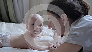 Mother And Her Newborn Baby Lie On Their Stomach In A Bed Opposite Each Other