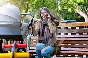 Mother with her newborn baby in the park talking on her mobile phone