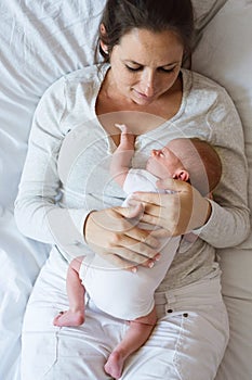 Mother with her newborn baby son lying in bed