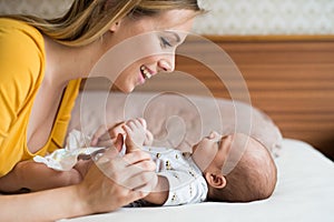 Mother with her newborn baby son lying on bed