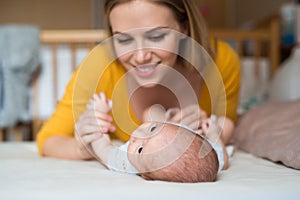 Mother with her newborn baby son lying on bed