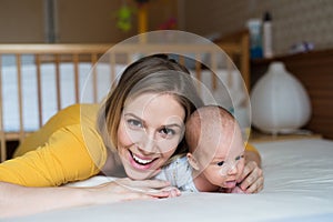 Mother with her newborn baby son lying on bed