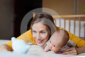 Mother with her newborn baby son lying on bed