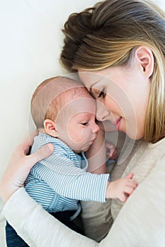 Mother with her newborn baby son lying on bed