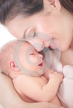 Mother and her newborn baby together. Happy mother and baby kissing and hugging. Maternity concept