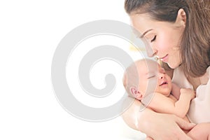 Mother and her Newborn Baby together. Love. Happy Mother and Baby kissing and hugging. High key soft image of Beautiful Family