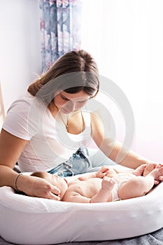 Mother with her newborn son on the bed in the rays of sunlight