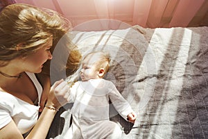 Mother with her newborn son lay on the bed in the rays of sunlight