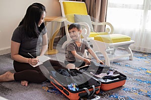 A mother and her son are packing clothes into their suitcases