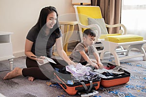 A mother and her son are packing clothes into their suitcases