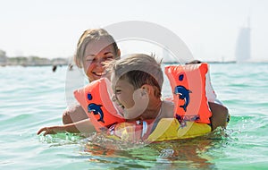 Mother and her son playing and running on the beach. Concept of friendly family