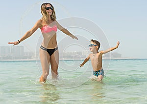 Mother and her son playing and running on the beach. Concept of friendly family