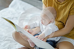 Mother and her son reading book in a bed before sleep. Familly story telling concept