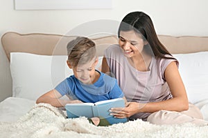 Mother and her son reading book together at home