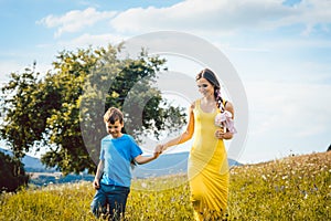 Mother with her son running on a summer meadow