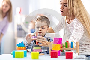 Mother and her baby son building toy pyramid tower