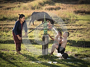 Mother her sons shower outdoor from Groundwater pump.