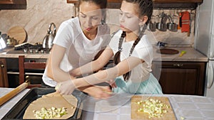 Mother and her teen daughter are cooking apple pie apfelstrudel together in the kitchen.