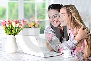 Mother and her teenage daughter using laptop at home