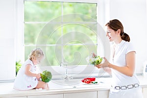 Mother and her toddler daughter cooking healthy salad