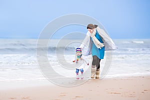 Mother and her toddler daughter running on beach