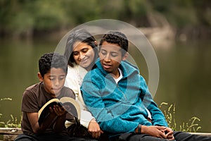 Mother With her Two Boys Studying the Bible by River Front