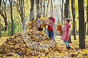 Mother and her two children gather fallen leaves photo