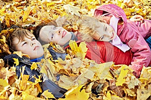 Mother and her two children lie in autumn park in photo