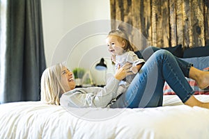 Mother and his baby daughter on bed having fun