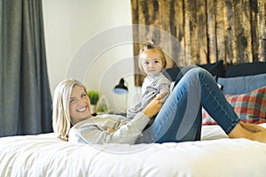 Mother and his baby daughter on bed having fun