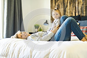 Mother and his baby daughter on bed having fun