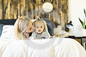 Mother and his baby daughter on bed having fun