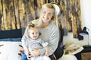 Mother and his baby daughter on bed having fun