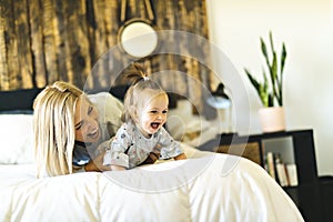 Mother and his baby daughter on bed having fun