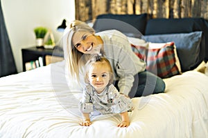 Mother and his baby daughter on bed having fun