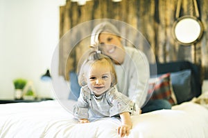 Mother and his baby daughter on bed having fun