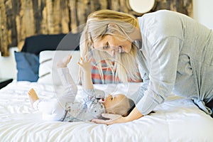 Mother and his baby daughter on bed having fun